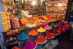 Photo Trader on colourful market stall (selling pigments and kumkum powder, incense, oil lamps etc. for Hindu worship) at night, Devaraja Market, Mysore, Karnataka, India 