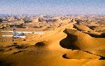 Photo Petit avion volant au-dessus de dunes de sable géantes dans la lumière du matin, Grand Erg Oriental, Algérie