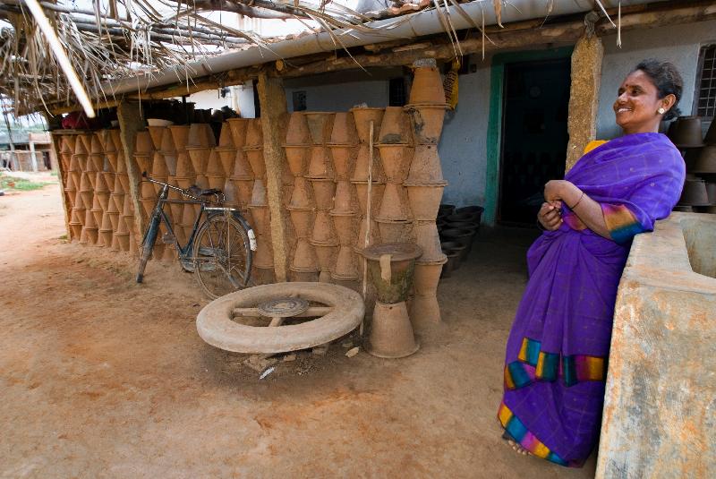 Photo Village potter avec roue de poterie et pots à l'extérieur de sa maison à Kurubura Kunte, Karnataka, Inde