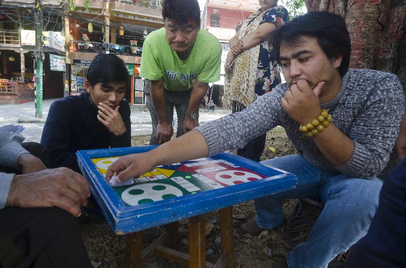 Photo Népalais hommes jouer jeu de société (ludo) sur un chautaara, Pokhara, Népal