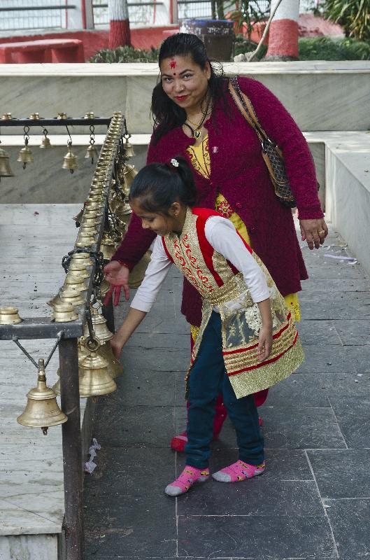 Photo Mère et fille sonnant rangée de cloches du temple hindou