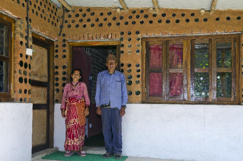 Couple de village népalais à l'extérieur de leur Bottle House construit après le tremblement de terre de 2015