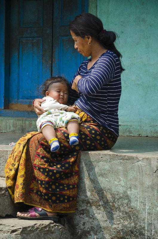 Mère avec une petite fille endormie sur ses genoux dans le village de montagne népalais